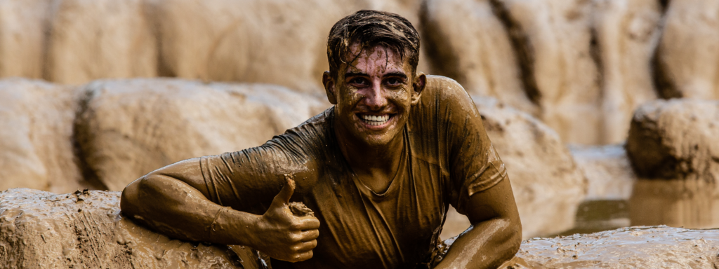 Junge, der während der Strong Viking Mud Edition Mud Run Schlammlauf komplett mit Schlamm bedeckt ist