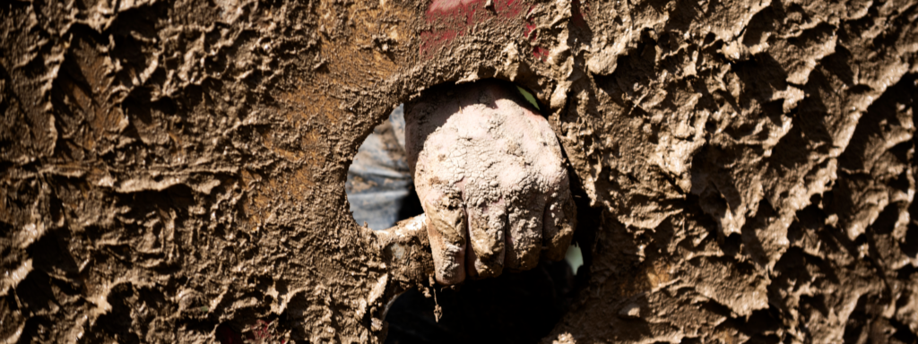 close-up van een hand dat een schild vasthoudt, alles zit onder de modder