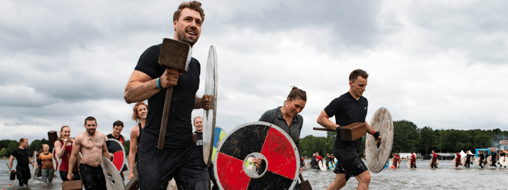 Härteste Fitness-Sprüche für wahre Wikinger, die dich durch den Hindernislauf bringen – genau wie die Leute auf den Bildern, die Schilde und Äxte durchs Wasser tragen.