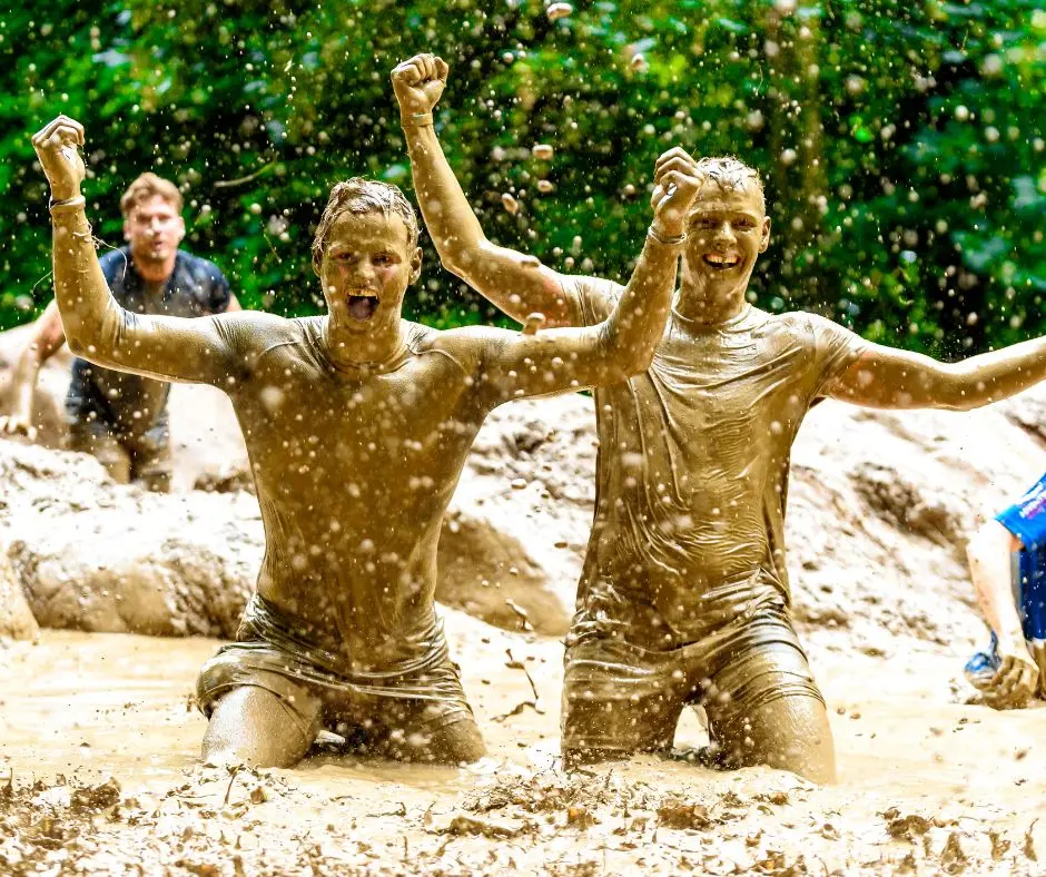 twee jongens tijdens de 7km lightning obstacle run van strong viking die onder de modder zitten