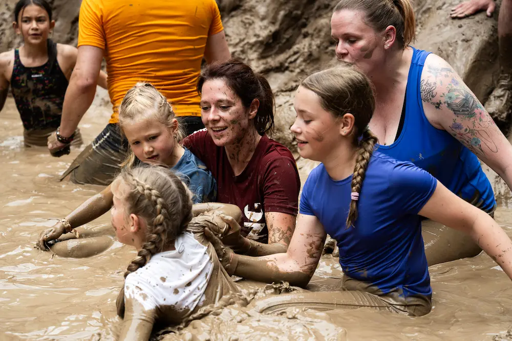 Kinderen met moeder in de modder tijdens de family run
